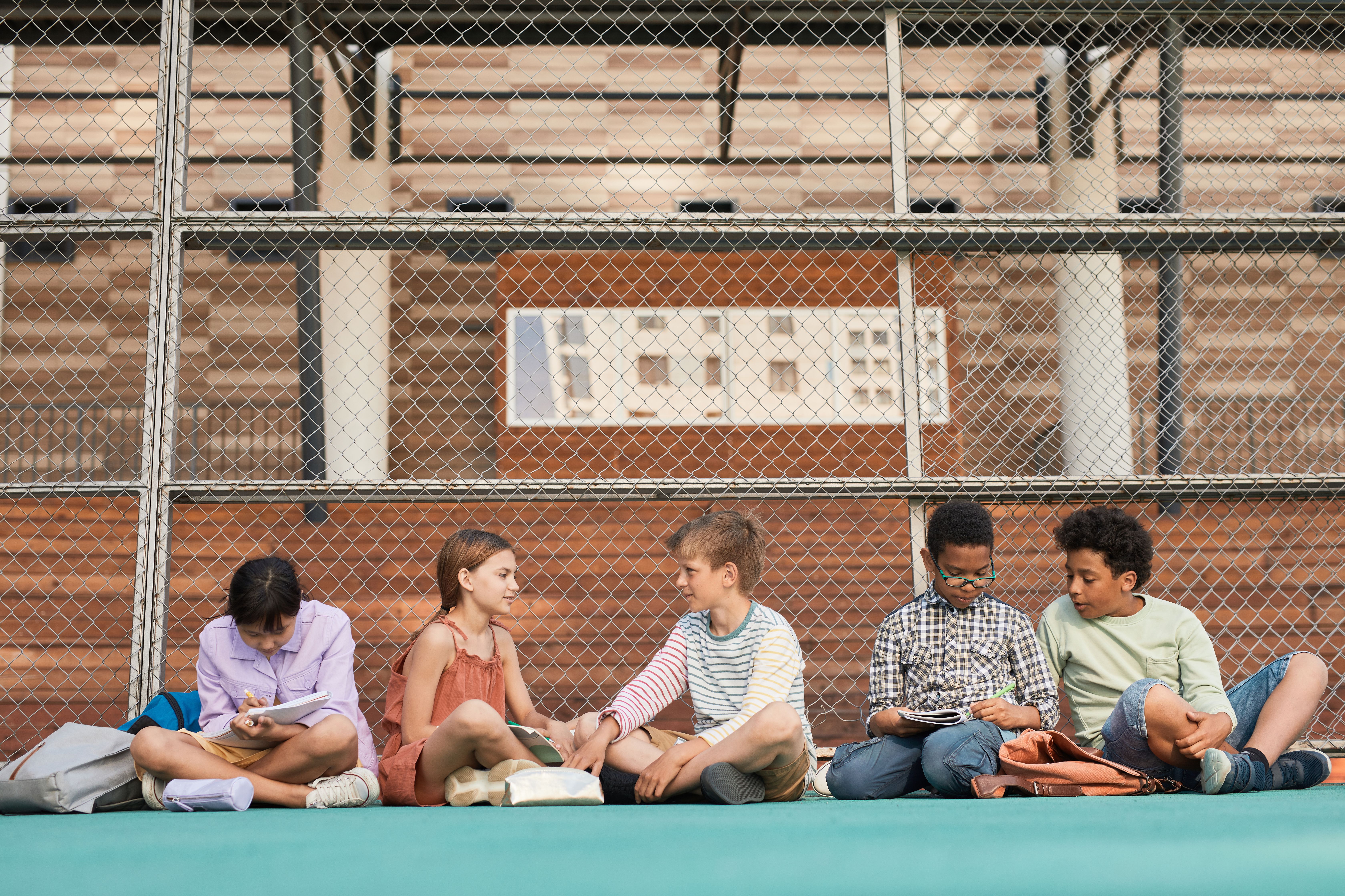 Children socialising on school playground - outdoor environment and play are inspected during Ofsted breakfast club and after school club visits